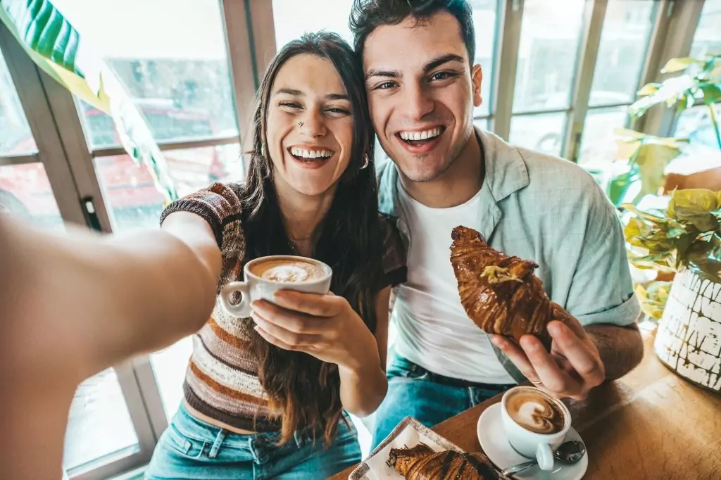 Happy couple enjoying breakfast drinking coffee at bar cafeteria