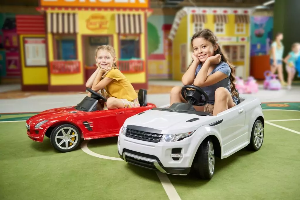 Happy kids sitting in electric toy cars.